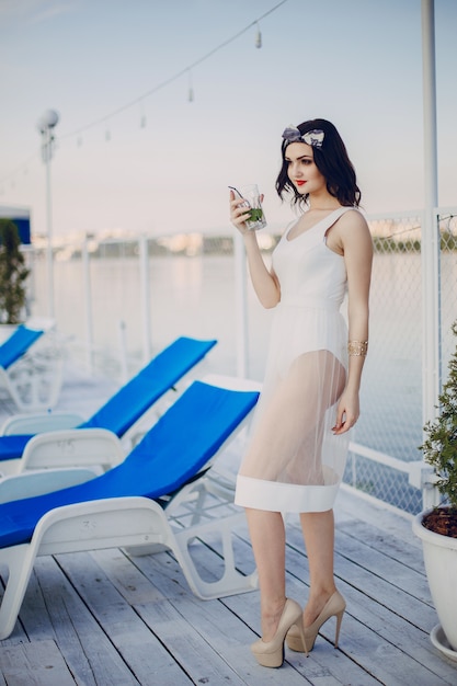 Chica jóven con un vestido blanco y una copa en la mano