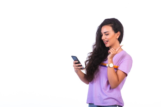 Foto gratuita chica joven con una videollamada con un teléfono inteligente negro