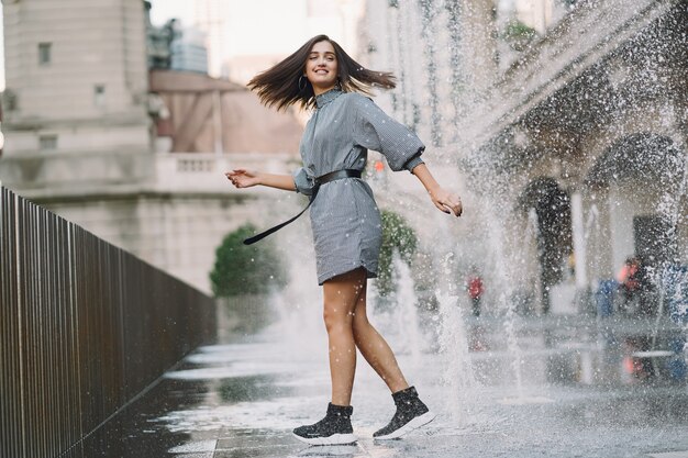 Chica jugando y bailando en una calle mojada