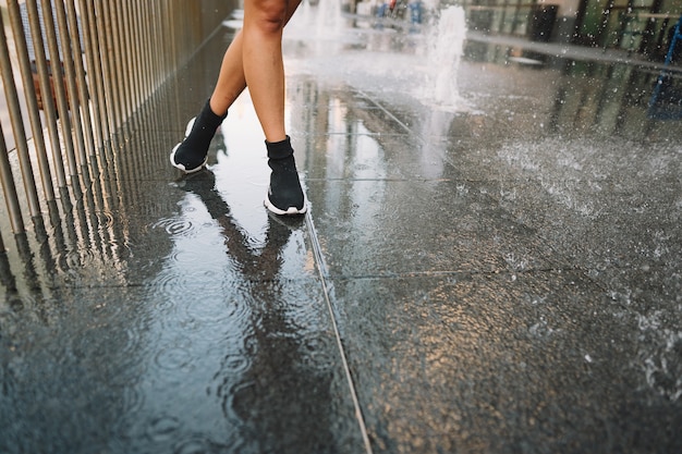 Chica jugando y bailando en una calle mojada