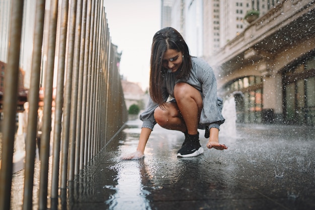 Chica jugando y bailando en una calle mojada