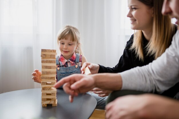 Chica jugando jenga con padres de cosecha