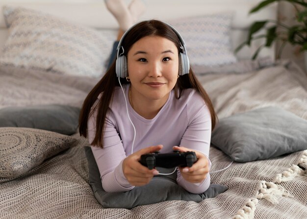 Chica jugando videojuegos en la cama full shot