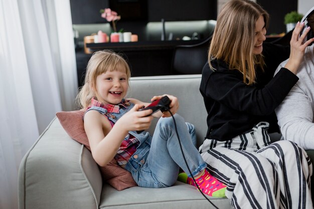 Chica jugando videojuegos cerca de los padres