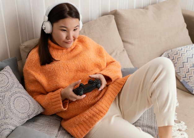 Chica jugando videojuegos en sofá tiro medio