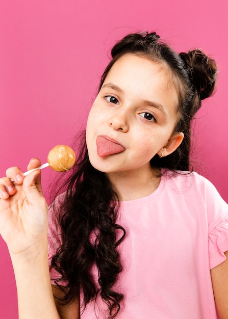 Chica juguetona con lengua afuera comiendo piruleta