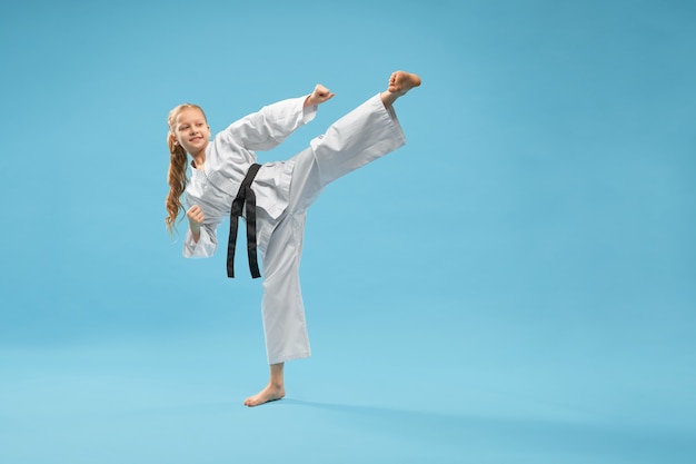 Chica de karate en kimono blanco practicando artes marciales.