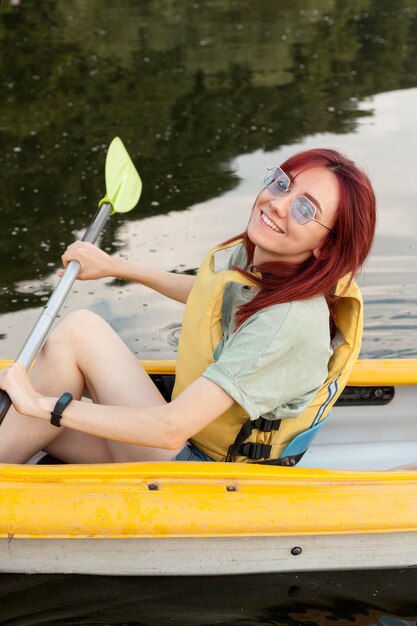 Chica en kayak sonriendo y sosteniendo la paleta