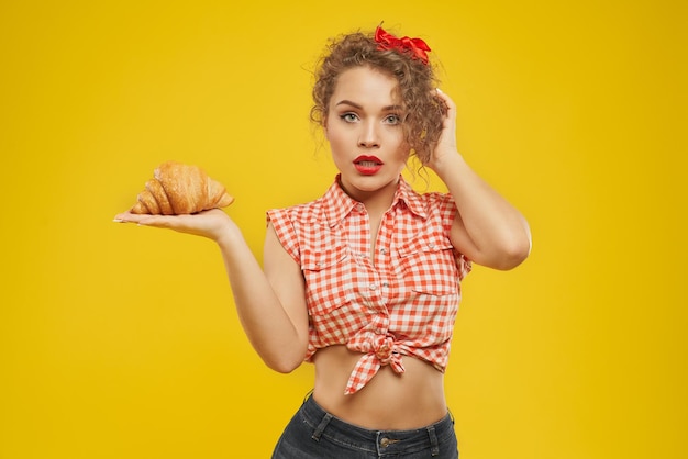 Chica con labios rojos sosteniendo croissant de palma