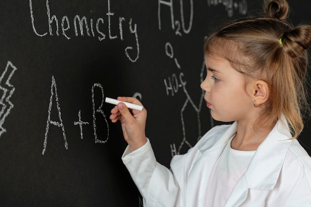 Foto gratuita chica en laboratorio con abrigo escribiendo