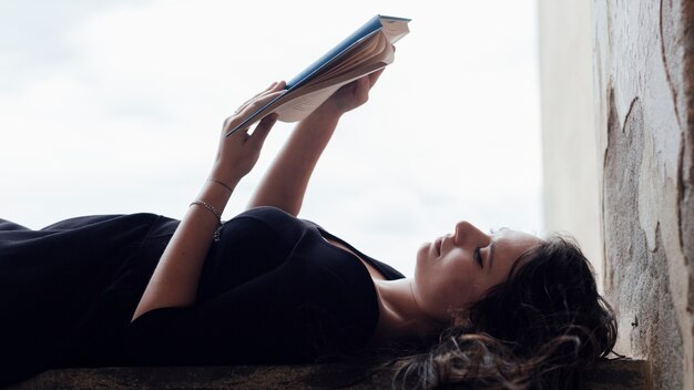 Chica leyendo un libro boca arriba