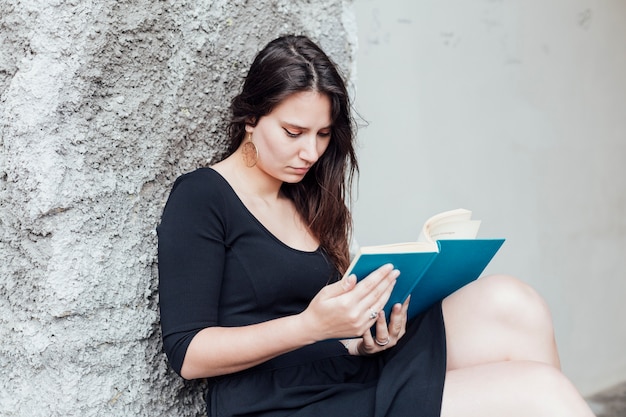 Chica leyendo un libro en la calle