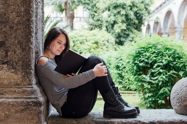 Chica leyendo un libro en la calle