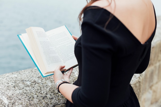 Foto gratuita chica leyendo un libro cerca del mar