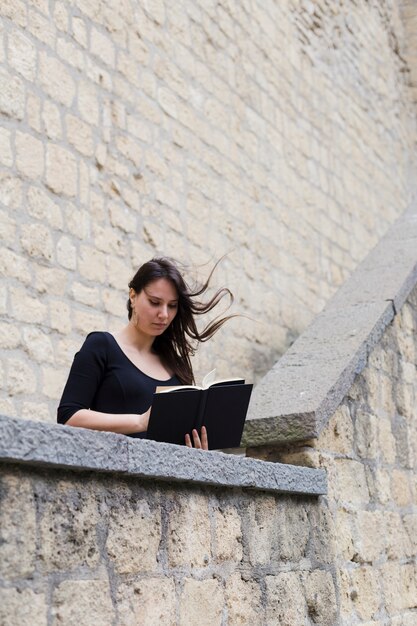 Chica leyendo un libro en un día de viento