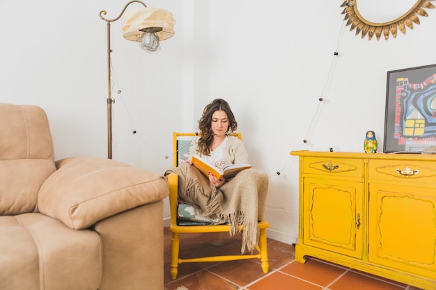 Foto gratuita chica leyendo un libro sentada en una silla