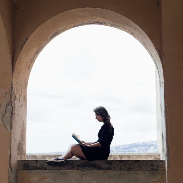 Chica leyendo un libro en una ventana