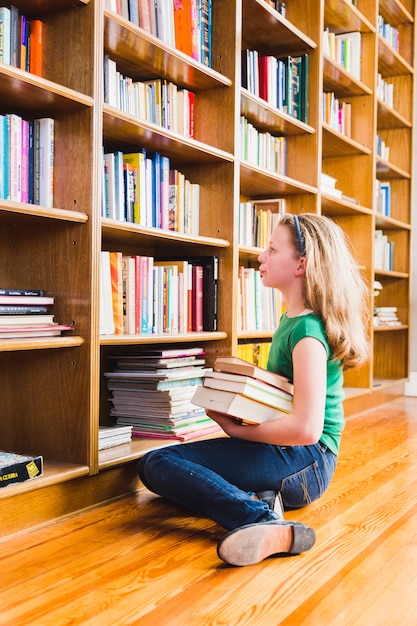 Chica con libros sentado en estanterías