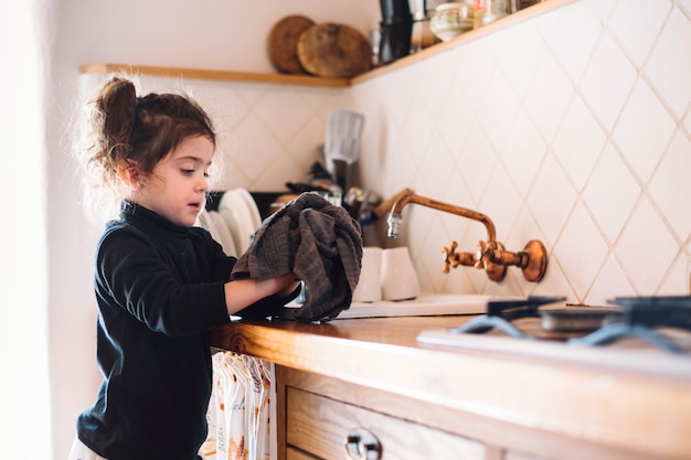 Foto gratuita chica limpiando su mano con una toalla en la cocina