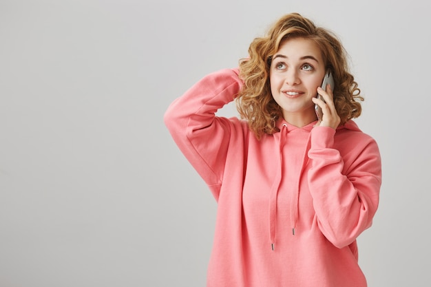 Chica linda despistada rascarse la cabeza pensativa como hablando por teléfono