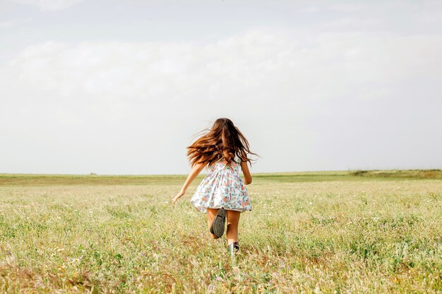 Chica en lindo vestido corriendo en el campo