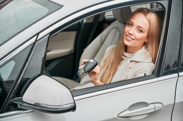 Chica con llaves en manos sentada en el asiento del conductor del coche