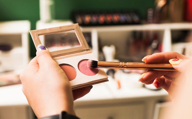 Chica llenando brocha con maquillaje