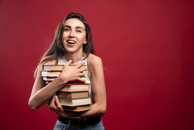 Chica lleva una pesada pila de libros