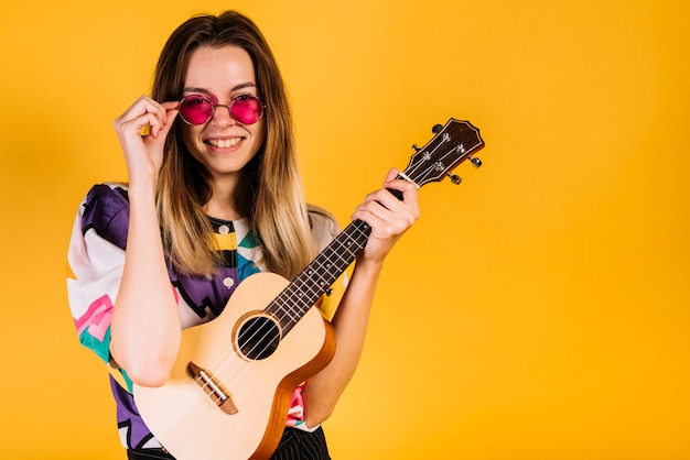 Foto gratuita chica llevando gafas con un ukelele