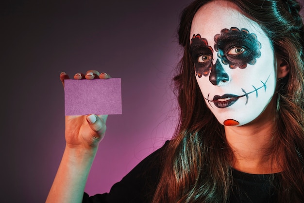 Chica con makeup de halloween mostrando tarjeta de visita