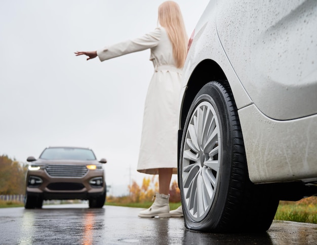 Chica con la mano extendida en la carretera que detiene el coche que se aproxima