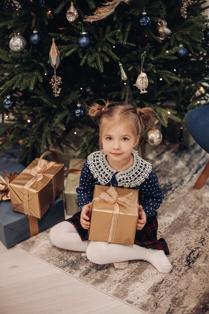 Chica manteniendo sus piernas debajo de ella y tomando una caja de regalo