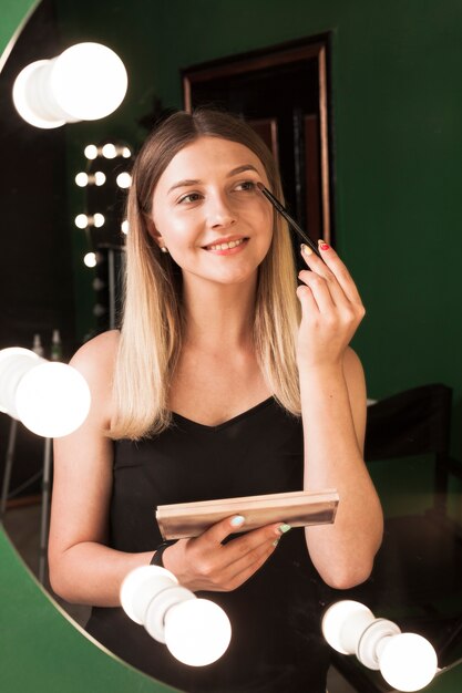 Chica maquillándose en una habitación verde