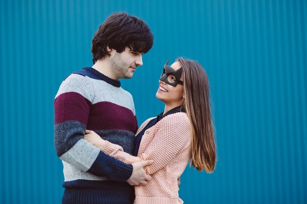 Chica con una máscara besando a su chico joven.