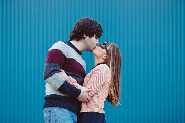 Chica con una máscara besando a su chico joven.