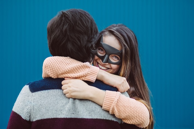 Foto gratuita chica con una máscara besando a su chico joven.