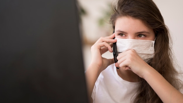 Chica con máscara hablando por teléfono