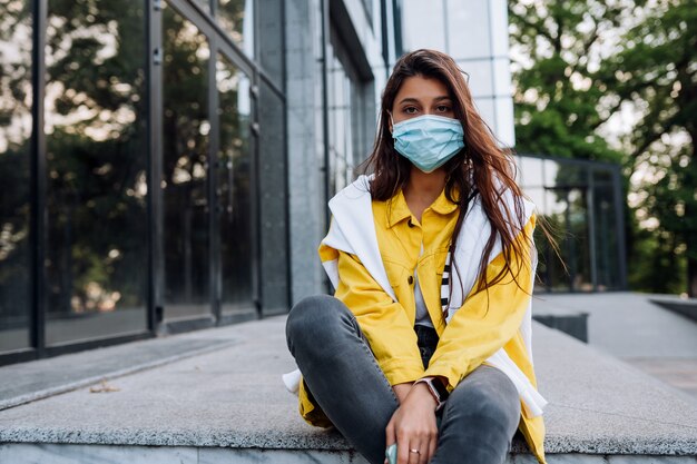 Chica con máscara posando en la calle. Moda durante la cuarentena del brote de coronavirus.