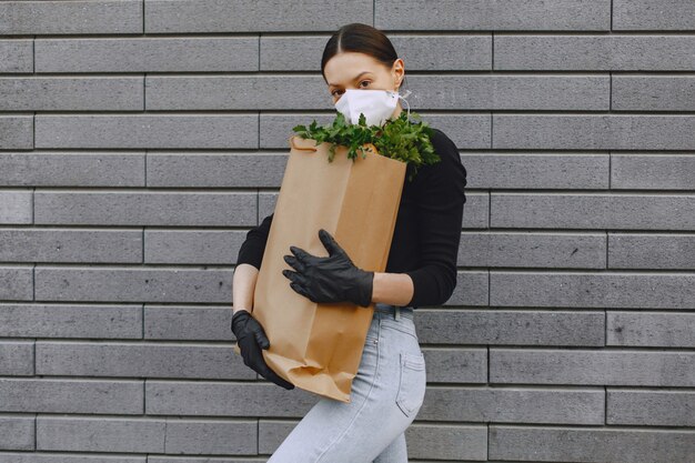 Chica con máscara protectora sostiene paquete con productos