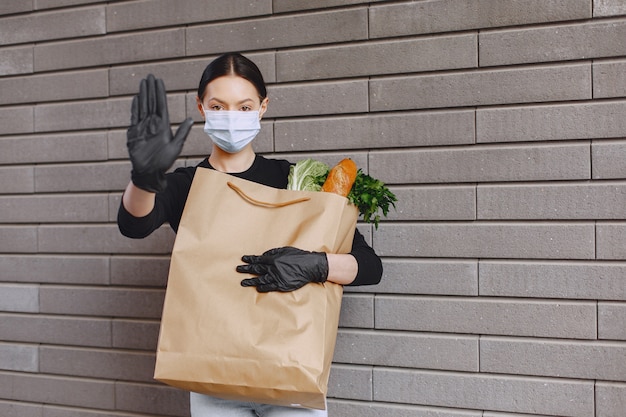 Chica con máscara protectora sostiene paquete con productos