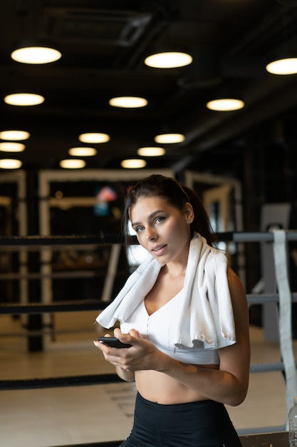 Chica mensajes de texto mientras toma un descanso en un gimnasio. Lee un mensaje