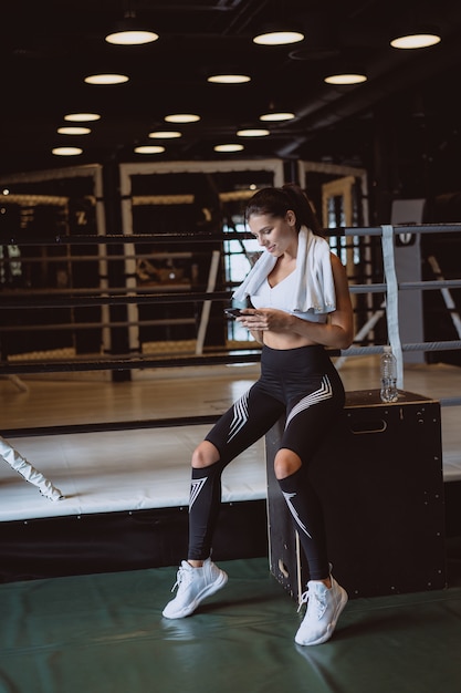 Chica mensajes de texto mientras toma un descanso en un gimnasio. Lee un mensaje