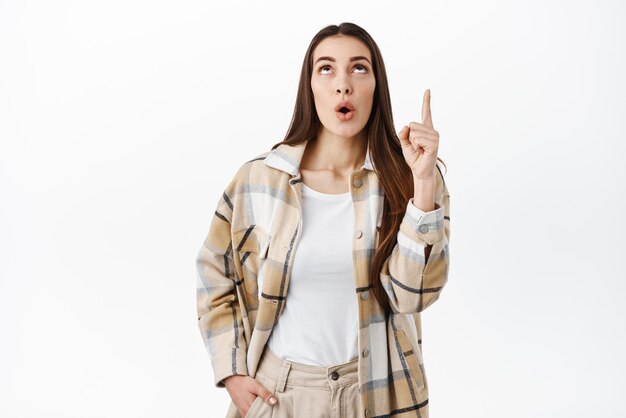 La chica mira y señala con interés leyendo suspiro o el logotipo apuntando a la pancarta en la parte superior que muestra un anuncio con una cara intrigada que dice wow de pie sobre un fondo blanco