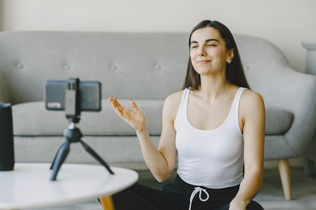 Foto gratuita chica mira el teléfono con cámara. comunicación online. entrenamiento en video