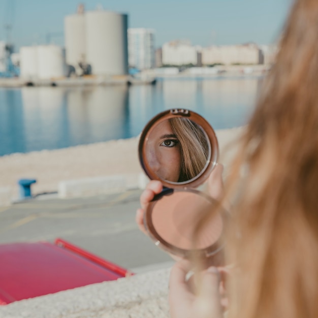 Foto gratuita chica mirando en espejo pequeño enfrente de puerto