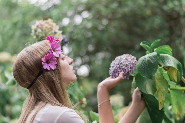 Chica mirando una flor con fondo borroso