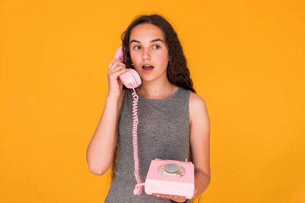 Chica mirando sorprendida mientras habla por teléfono