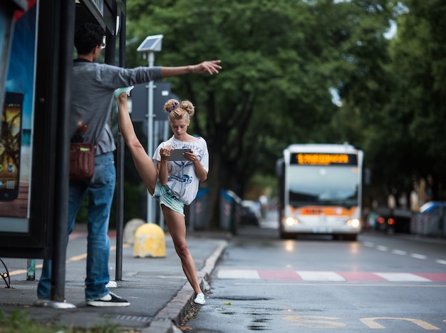 Chica mirando su móvil mientras levanta una pierna por encima de su cabeza