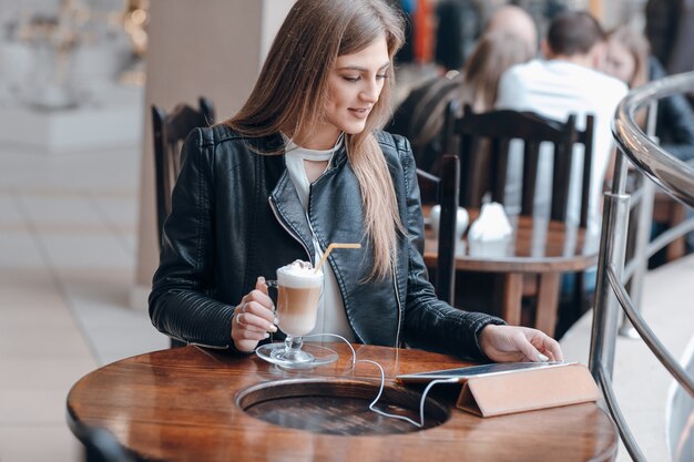 Chica mirando una tablet en una cafetería