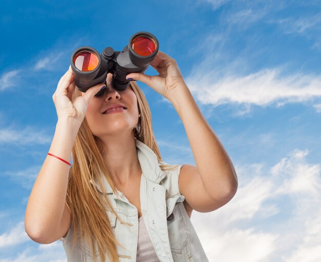 Chica mirando a través de prismáticos el cielo